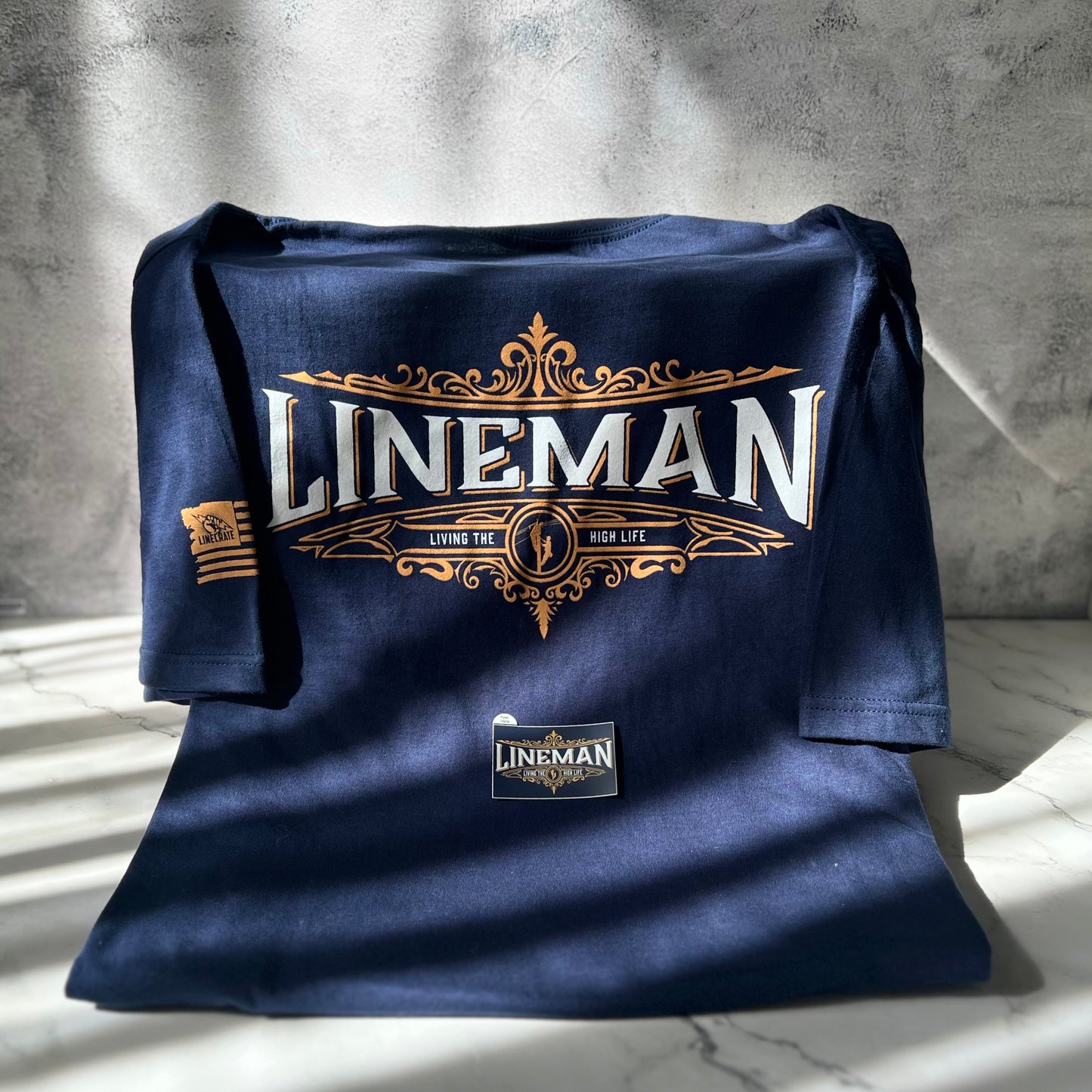 LineMan 'Living The High Life' navy t-shirt with matching sticker and LineCrate flag logo.
