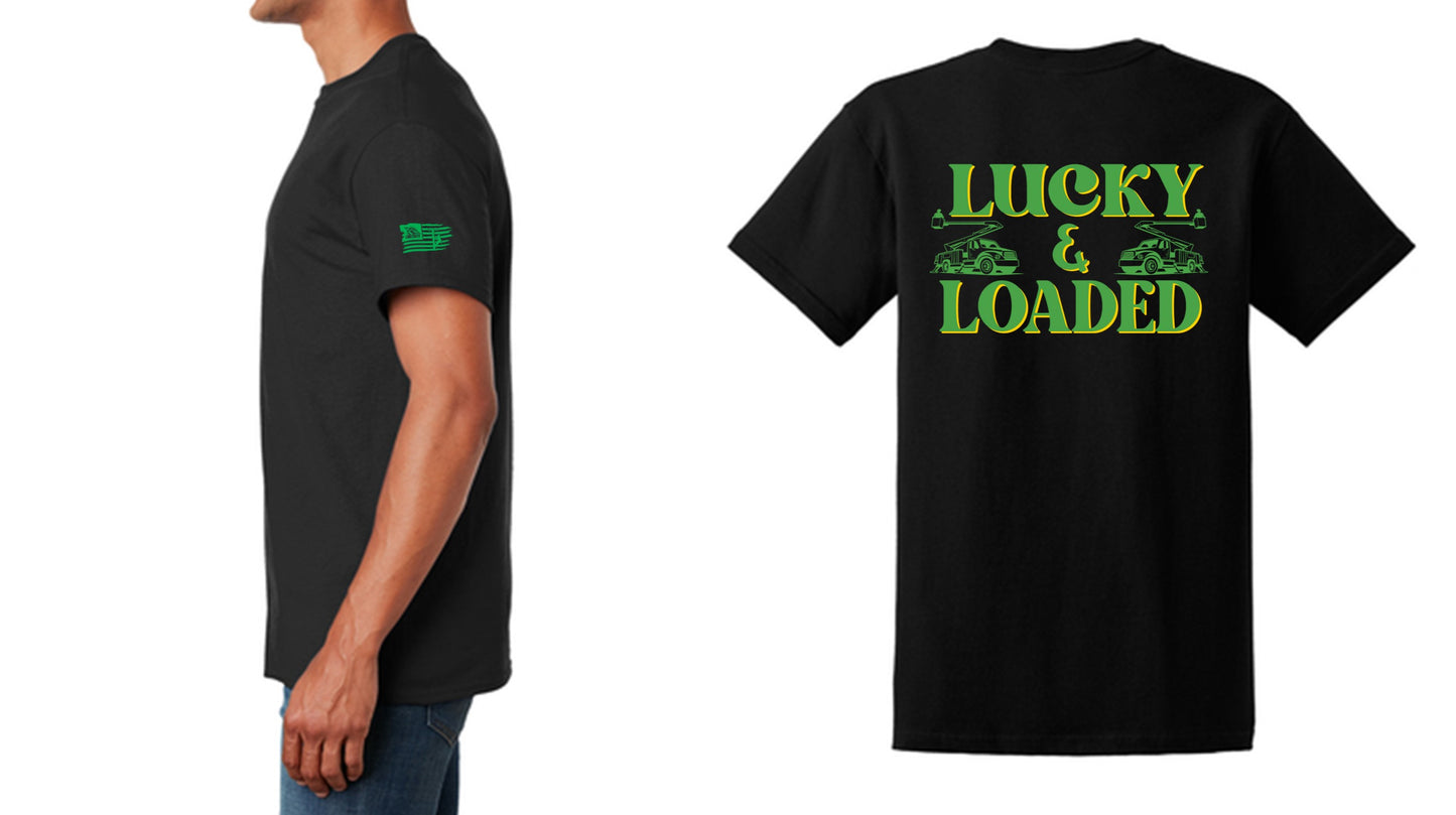 A black T-shirt featuring the bold text "Lucky & Loaded" in green and yellow, with two bucket trucks on either side of the text. The sleeve has the LineCrate logo and flag graphic. Designed for LineMen, this shirt showcases pride in the line trade with a modern fit and durable cotton fabric.