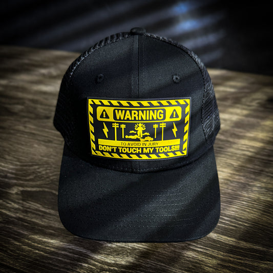 Black trucker hat with a yellow and black 'Warning: Don't Touch My Tools' graphic patch on the front.