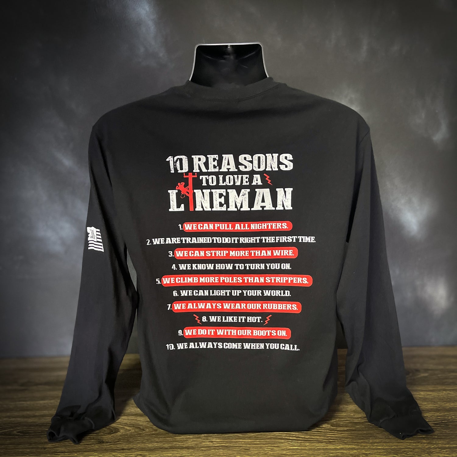 Long-sleeve black shirt featuring the design "10 Reasons to Love a LineMan" in bold white and red text on the back. A LineMan silhouette appears in the word "LineMan." The shirt also displays the LineCrate logo with a LineMan on a pole on the sleeve.