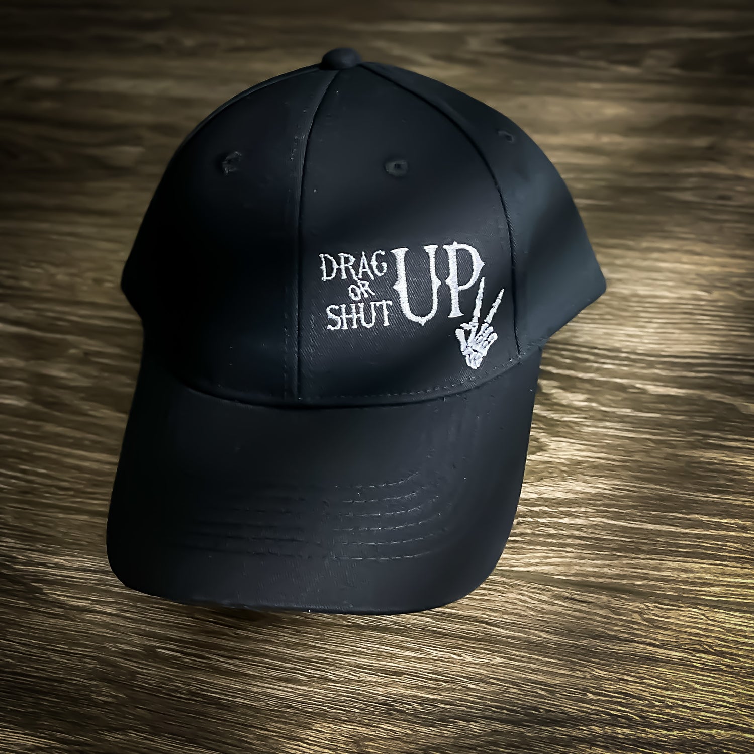 Black Drag Up or Shut Up hat with embroidered text and skeleton hand for linemen and blue-collar workers