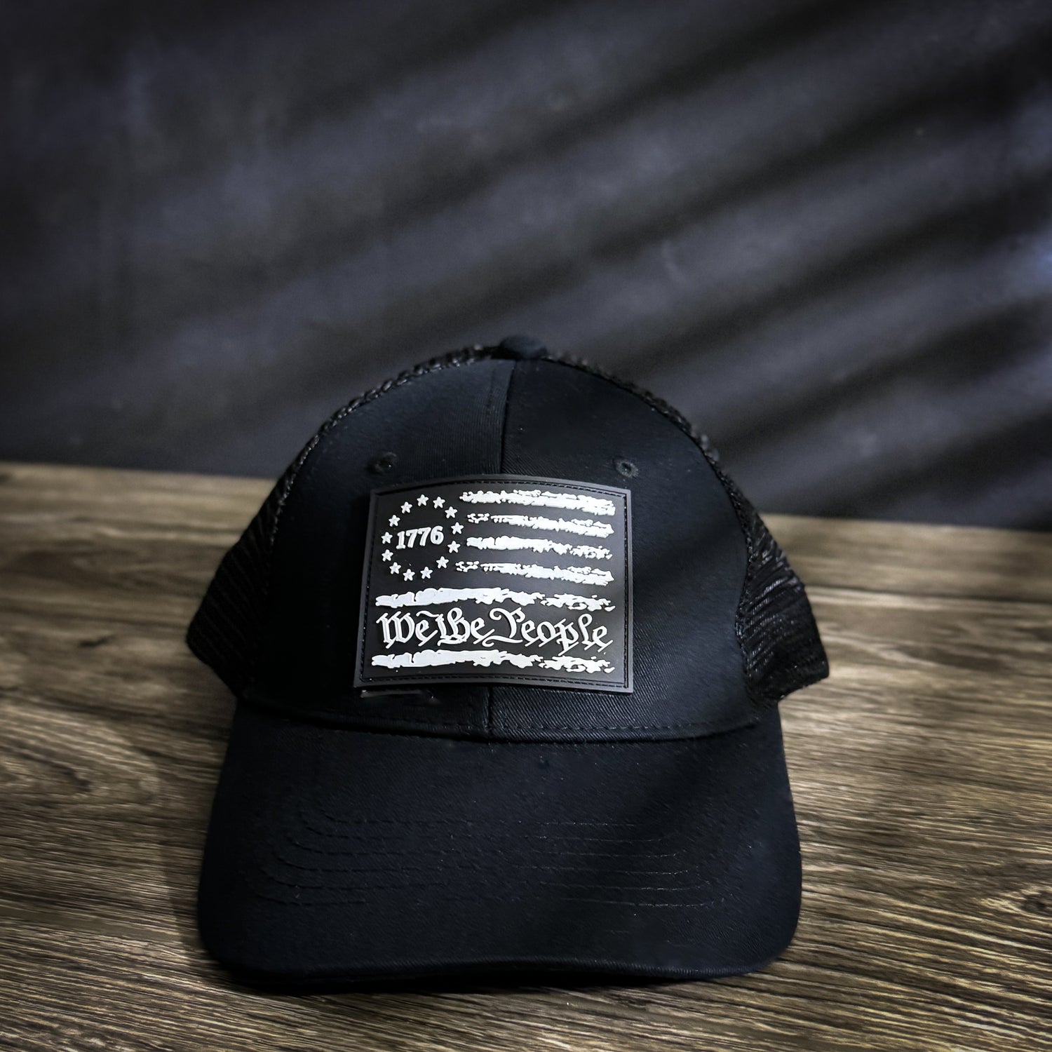 We The People trucker hat with 1776 flag rubber patch, mesh back, and snapback closure