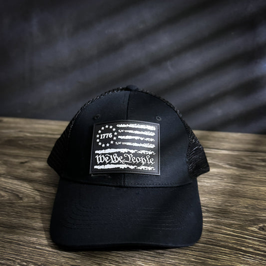 We The People trucker hat with 1776 flag rubber patch, mesh back, and snapback closure